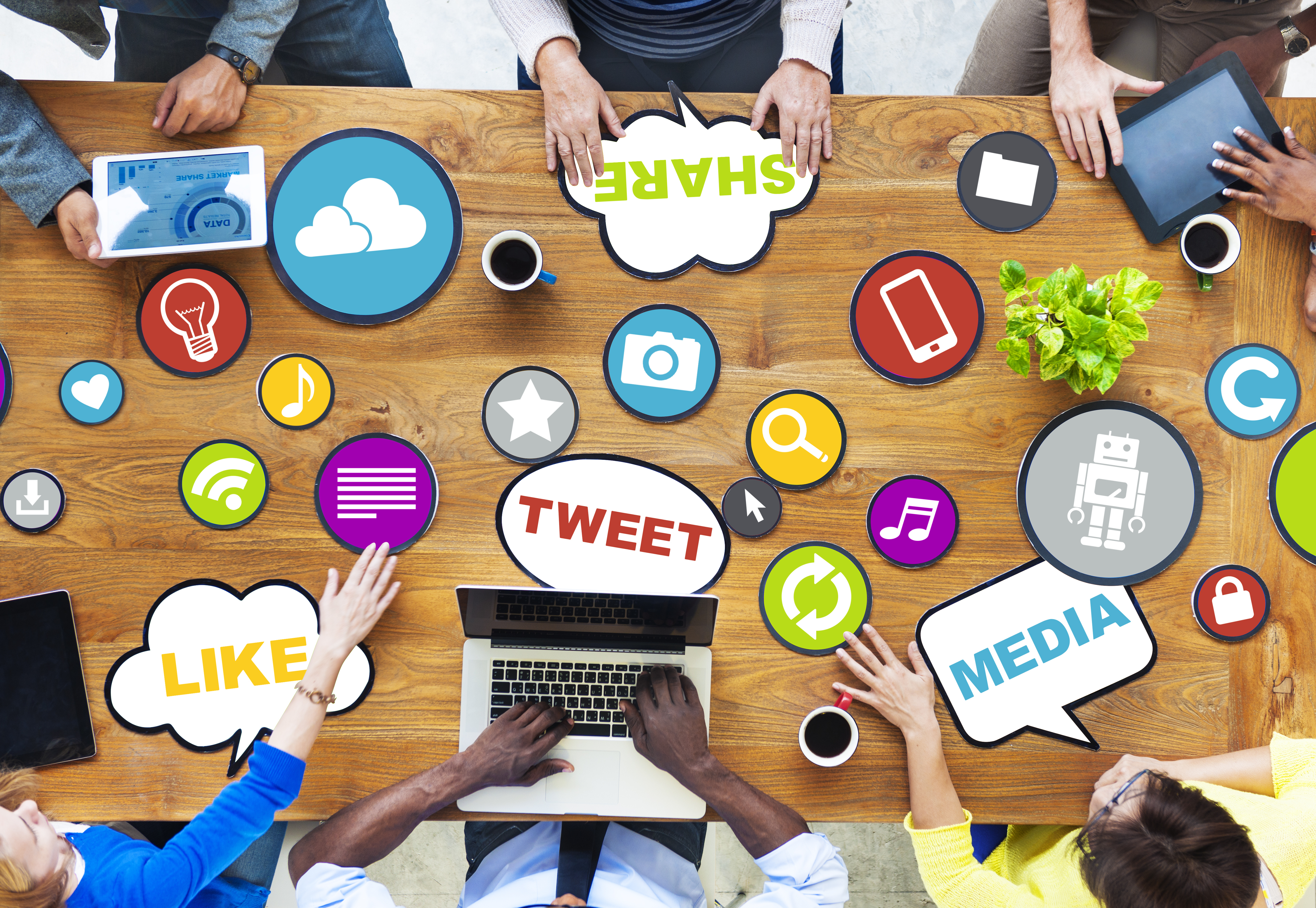 A meeting table with icons and speech bubbles for social media terminology such as share, like, tweet and media. 